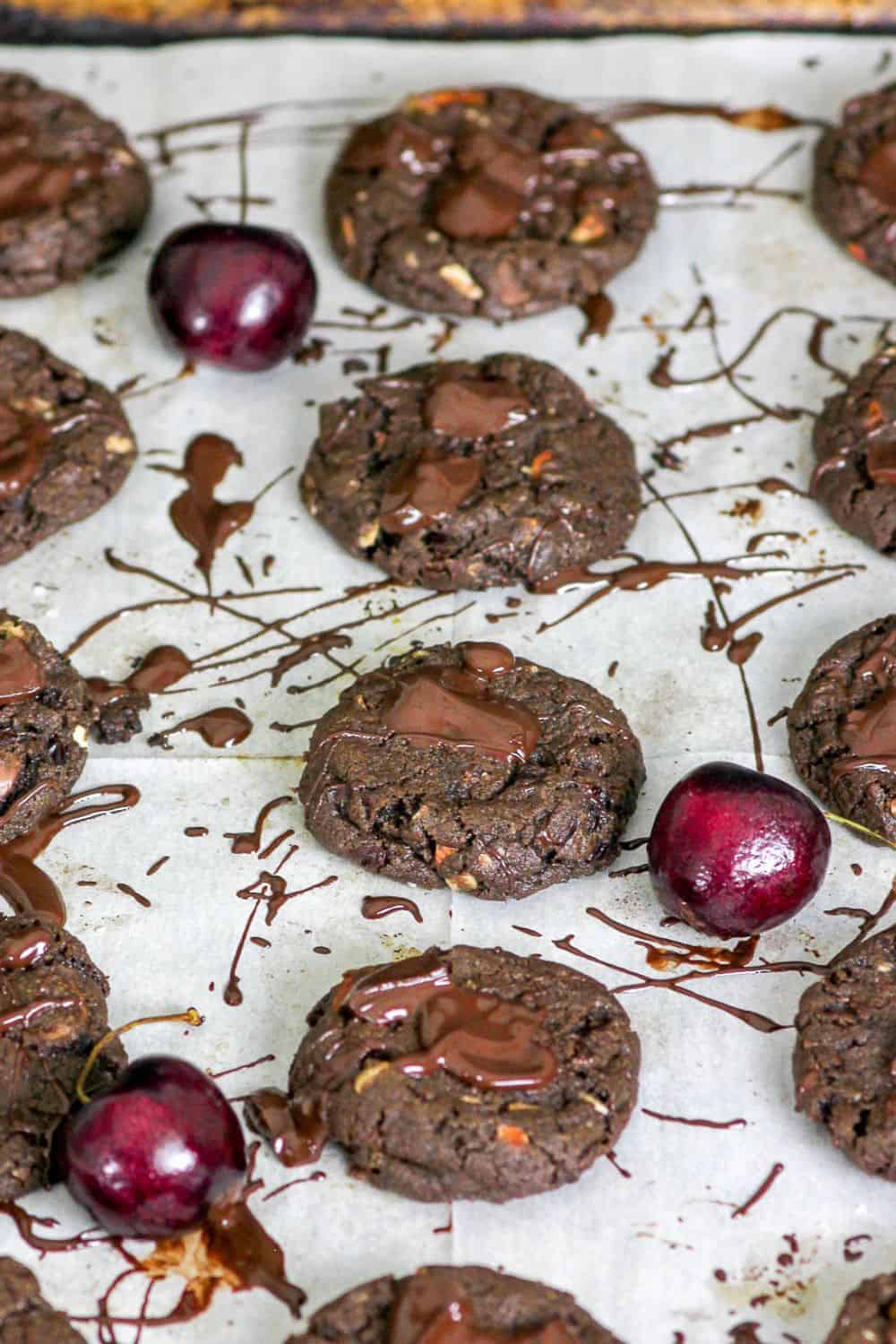 cookies on a tray with melted chocolate and cherries