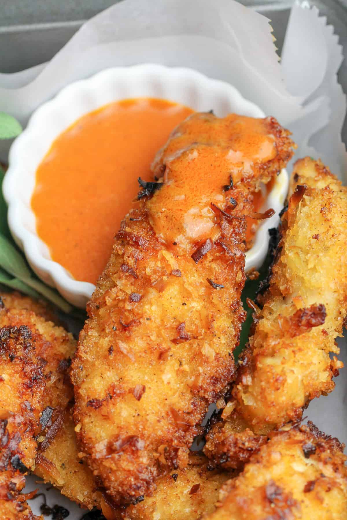 A Coconut Chicken Tender dipped in black pepper hot sauce