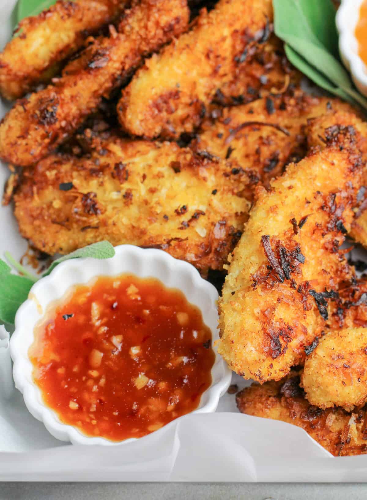Spicy Coconut Chicken Tenders next to a dish of sweet chili sauce