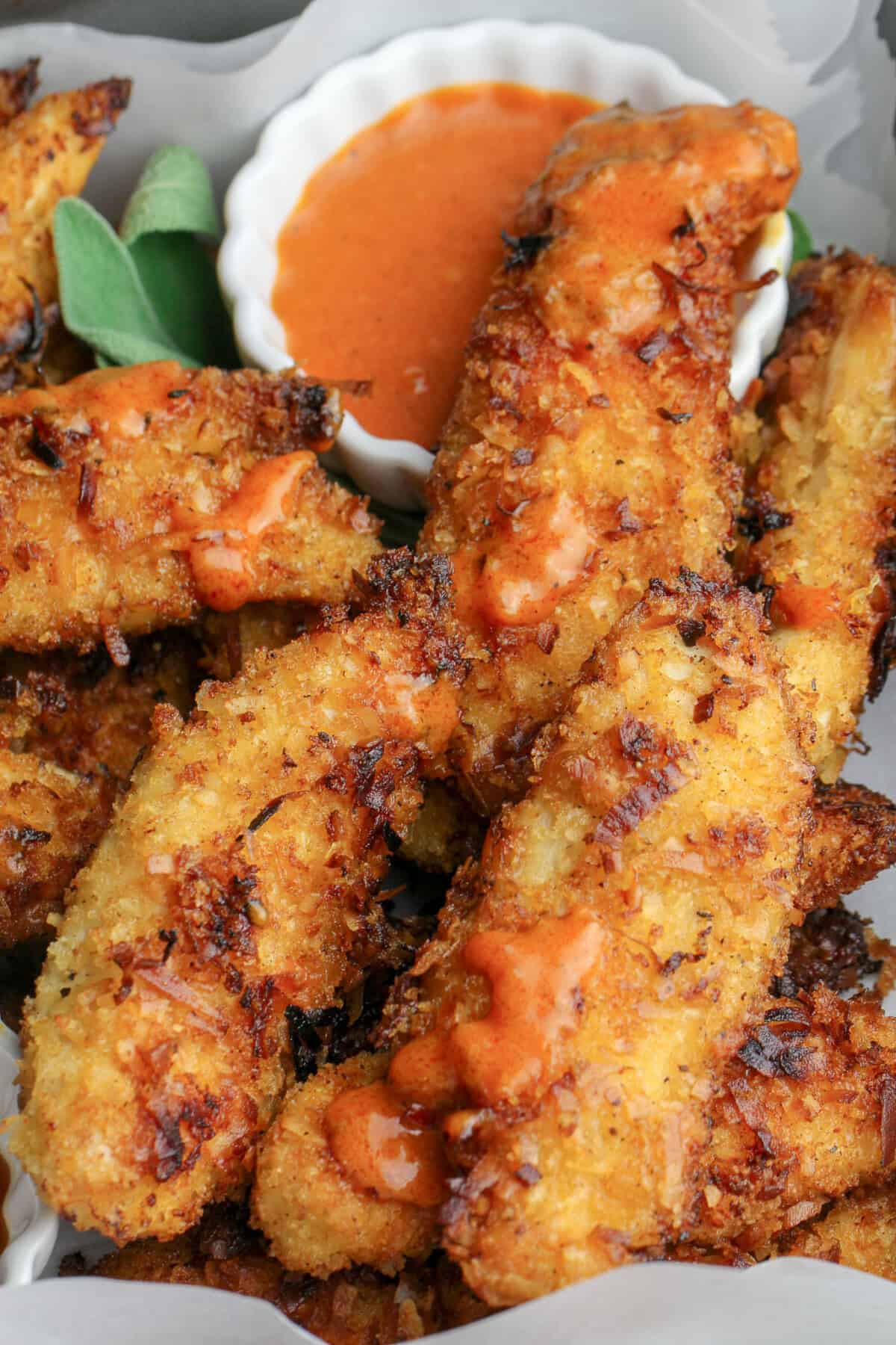 Close up of Coconut Chicken Tenders with black pepper hot sauce