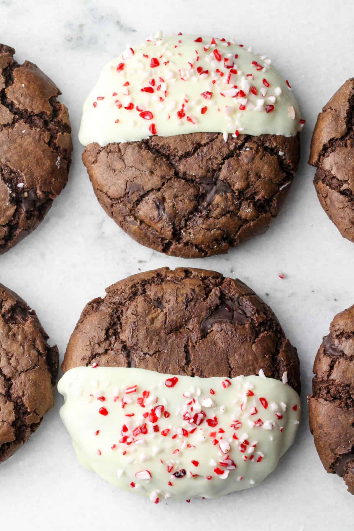 a row of chocolate cookies dipped in white chocolate and sprinkled with crushed peppermint