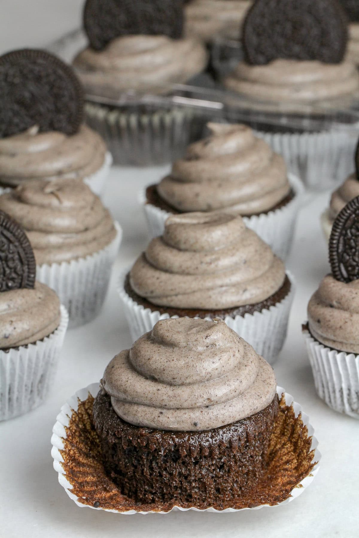 These super moist Oreo cupcakes have a hidden Oreo cookie inside, then topped with a cream cheese Oreo marshmallow frosting! Oreo Cupcakes on the counter, one with the liner pulled down