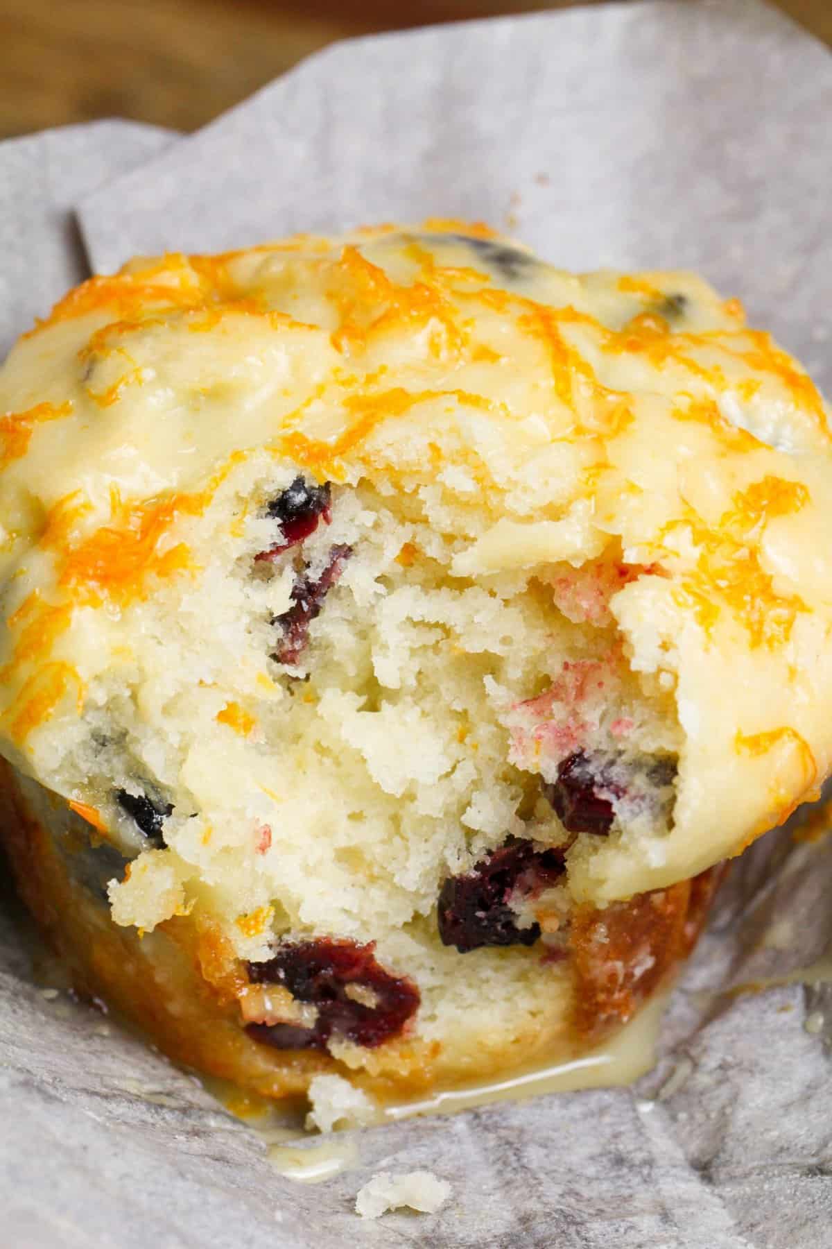 Tender, citrusy Orange Cranberry Muffins are buttery soft and topped with a tangy and vibrant orange glaze. No mixer needed! An orange cranberry muffin with a bite missing