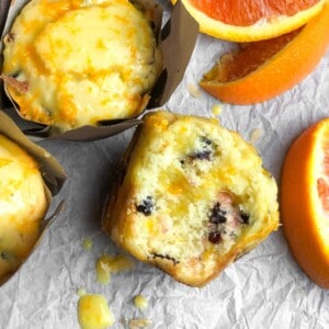 a table full of orange cranberry muffins next to orange slices