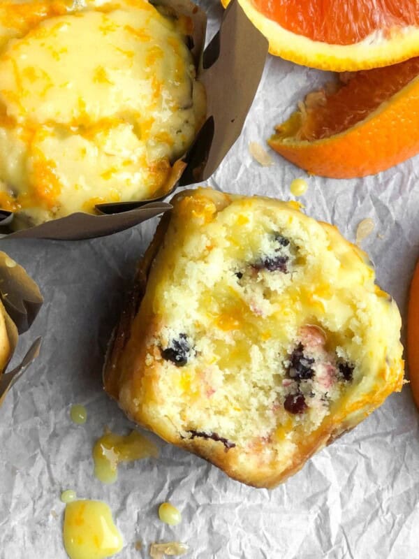 a table full of orange cranberry muffins next to orange slices