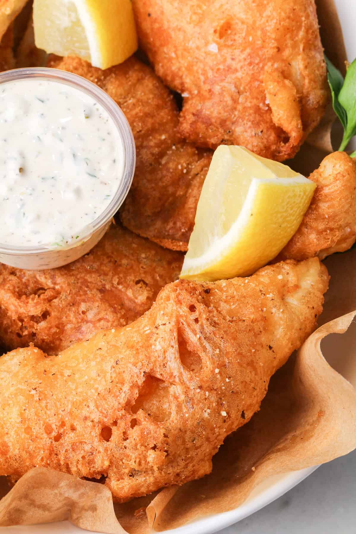 Halibut is coated in a beer batter that puffs up beautifully & is paired with crispy homemade fries to make the absolute BEST fish and chips. Close up of a plate of fish and chips