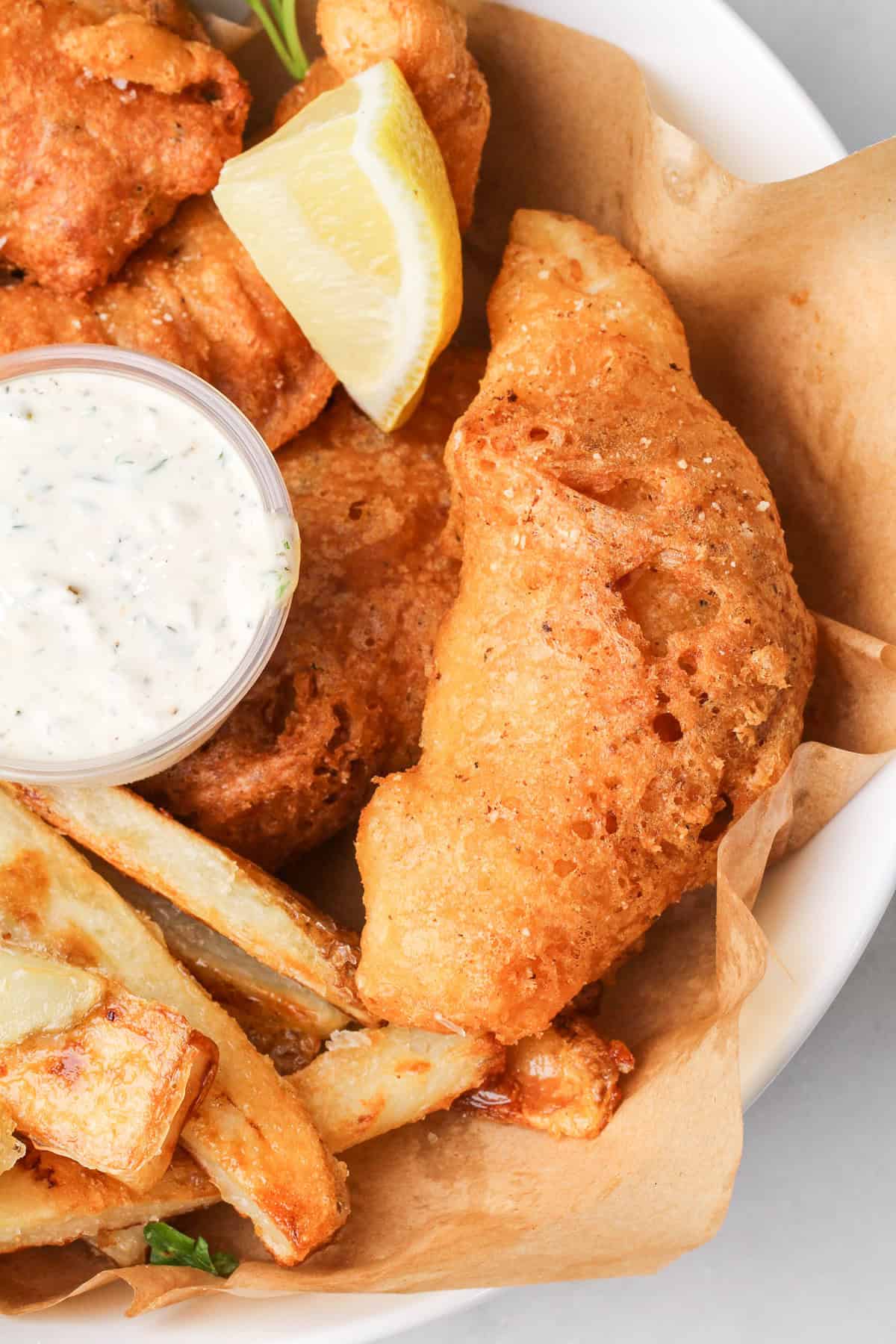 Halibut is coated in a beer batter that puffs up beautifully & is paired with crispy homemade fries to make the absolute BEST fish and chips. Overhead view of a plate of fish and chips