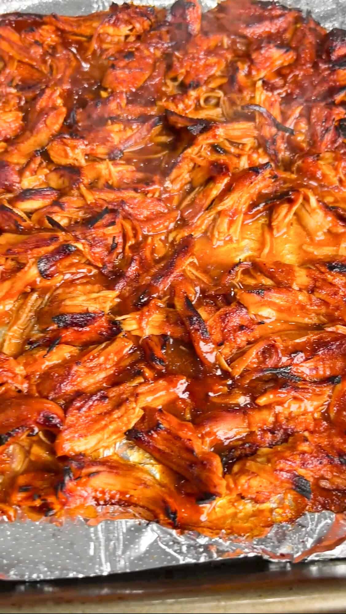 Shredded BBQ chicken, coleslaw tossed in Alabama white sauce, and crunchy chips make these BBQ Chicken Sliders unforgettable. Shredded BBQ chicken on a foil lined baking sheet