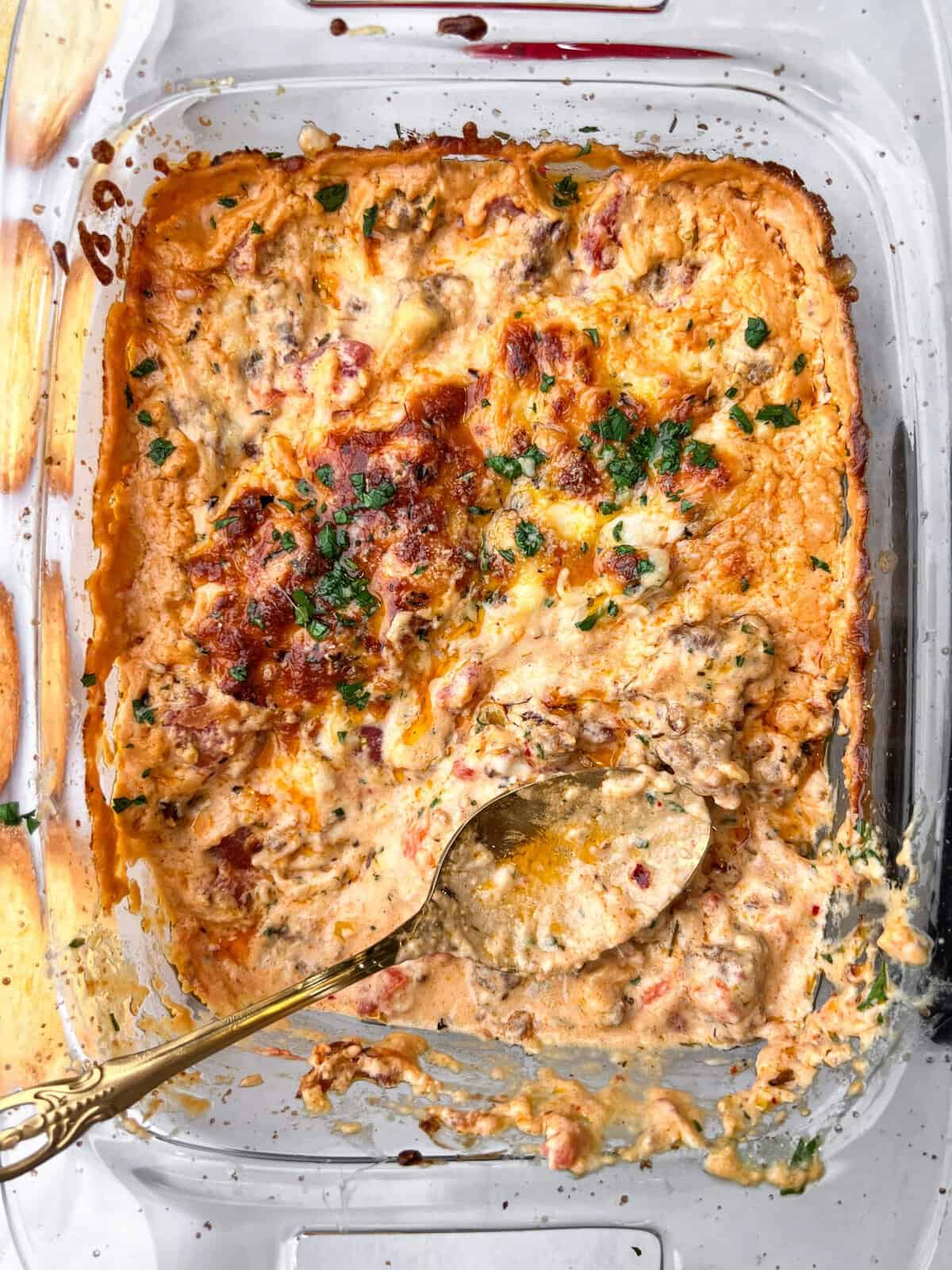 This 10-minute Spicy Italian Sausage Dip is made with mozzarella cheese, tangy pickled peppers, and hot sausage. Great for parties! A spoon in a baking dish of spicy Italian sausage dip