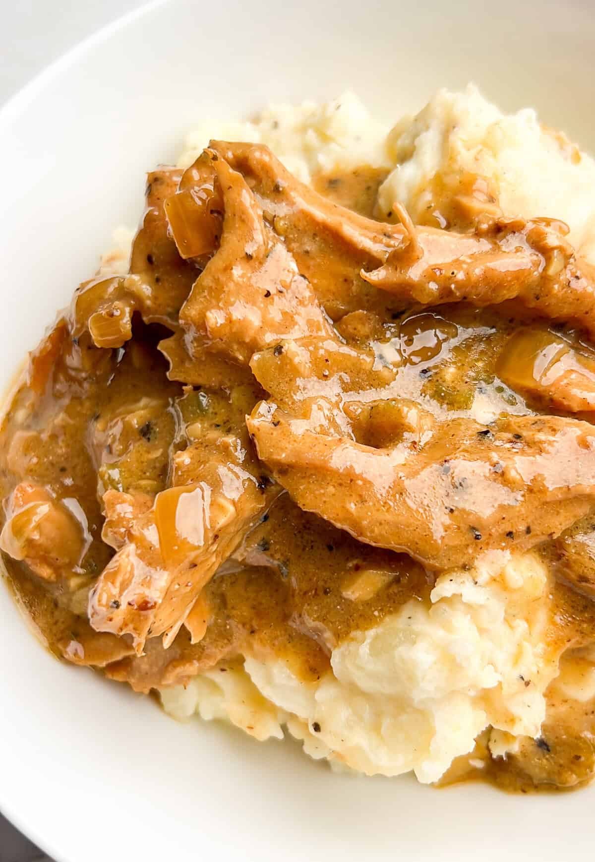 With tender chicken cooked in homemade pan gravy, Smothered Chicken and Gravy is classic Southern comfort food. Ready in 30 minutes! Smothered chicken and gravy in a bowl with mashed potatoes