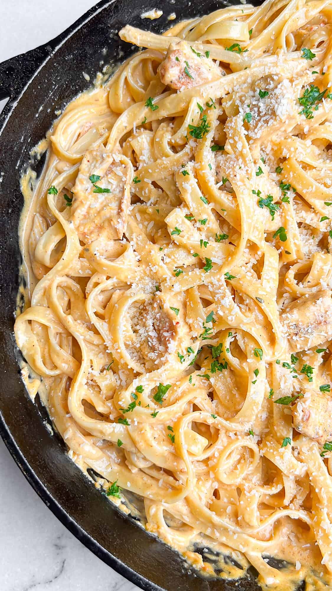 This buffalo chicken pasta recipe combines juicy chicken with tender fettuccine and a creamy, spicy alfredo-style sauce. Ready in 30 minutes! Overhead view of creamy buffalo chicken pasta in a large skillet.