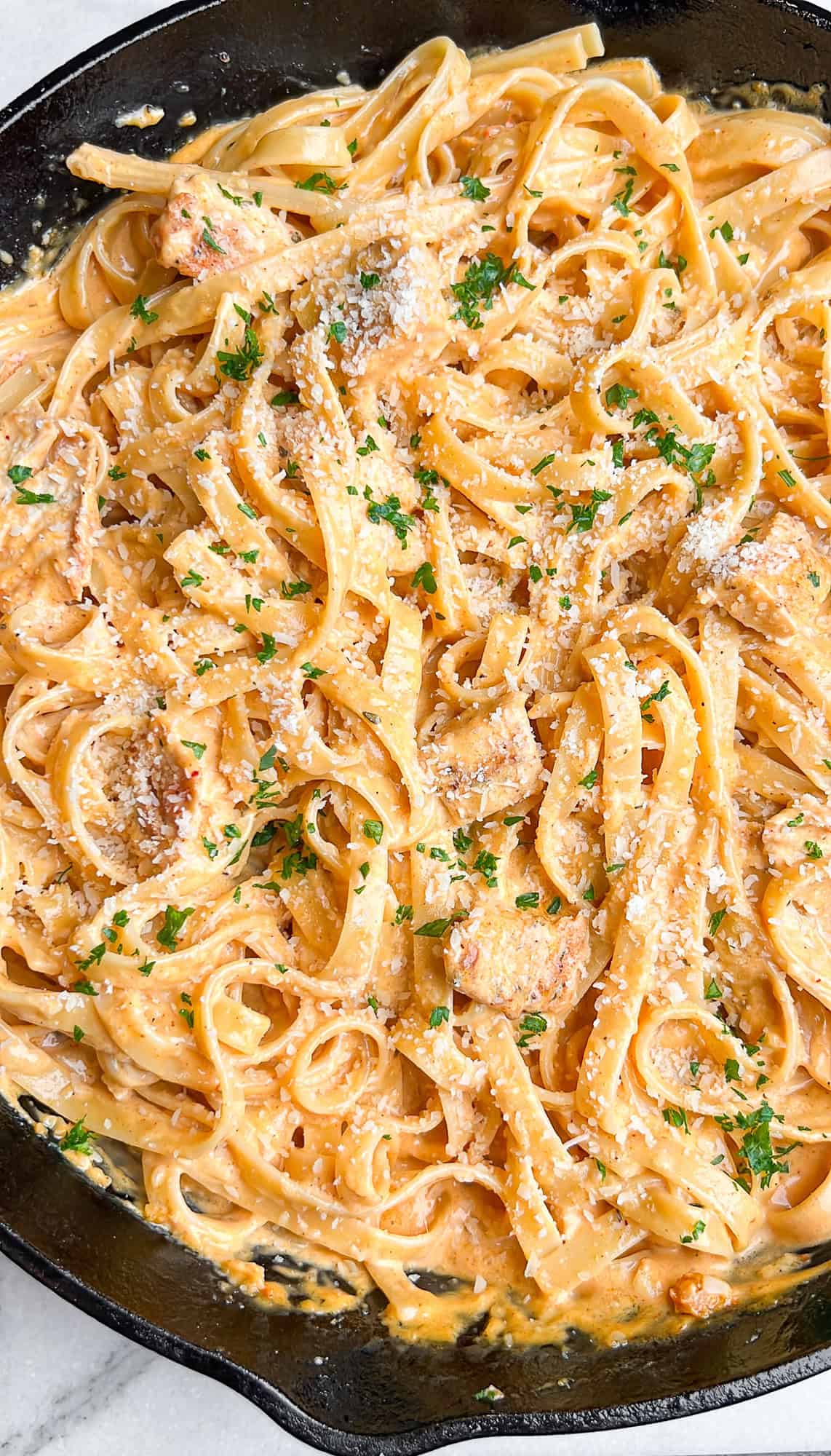 This buffalo chicken pasta recipe combines juicy chicken with tender fettuccine and a creamy, spicy alfredo-style sauce. Ready in 30 minutes! Overhead view of creamy buffalo chicken pasta in a large skillet.