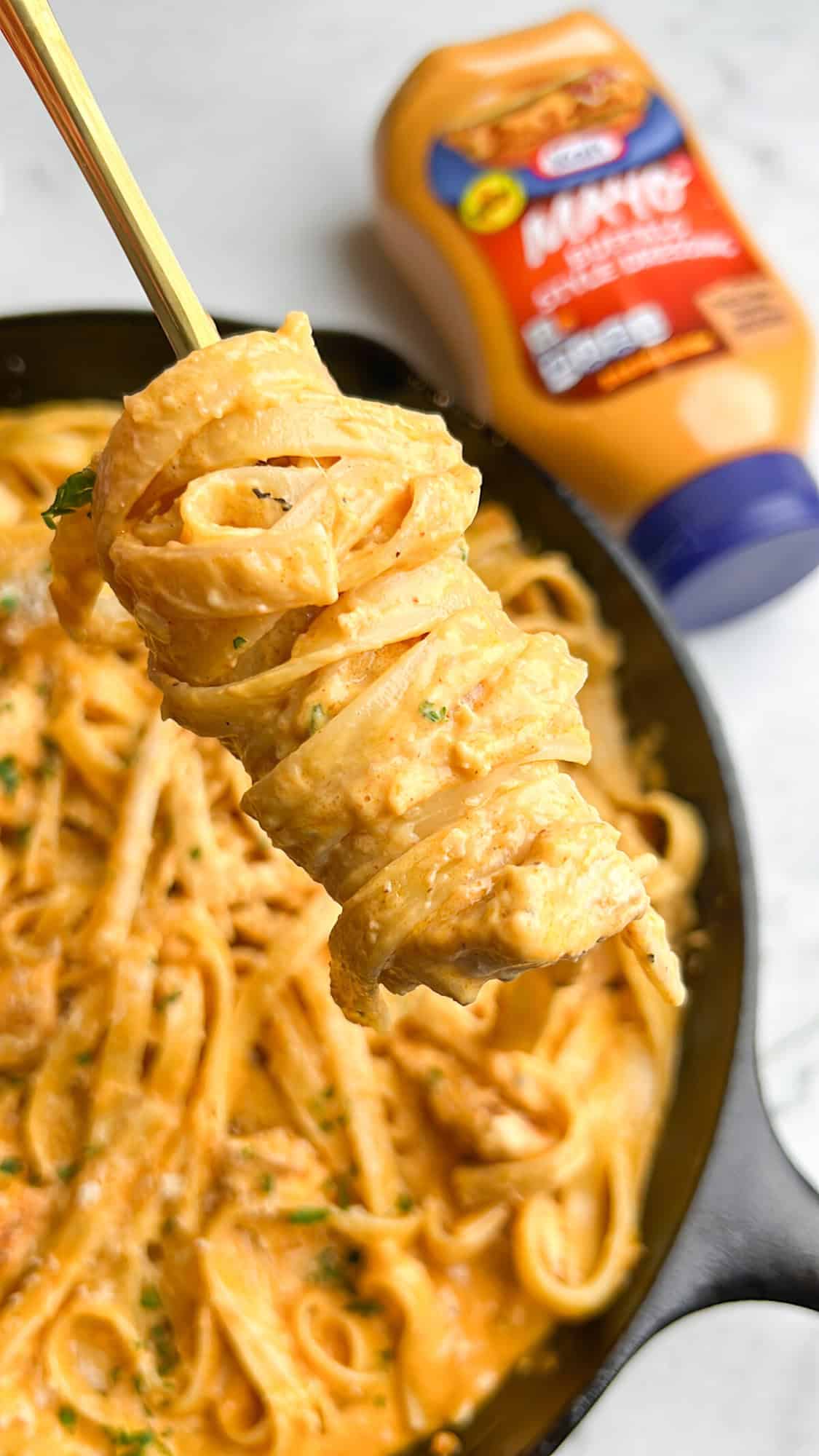 This buffalo chicken pasta recipe combines juicy chicken with tender fettuccine and a creamy, spicy alfredo-style sauce. Ready in 30 minutes! Creamy buffalo chicken pasta swirled on a fork above a skillet.