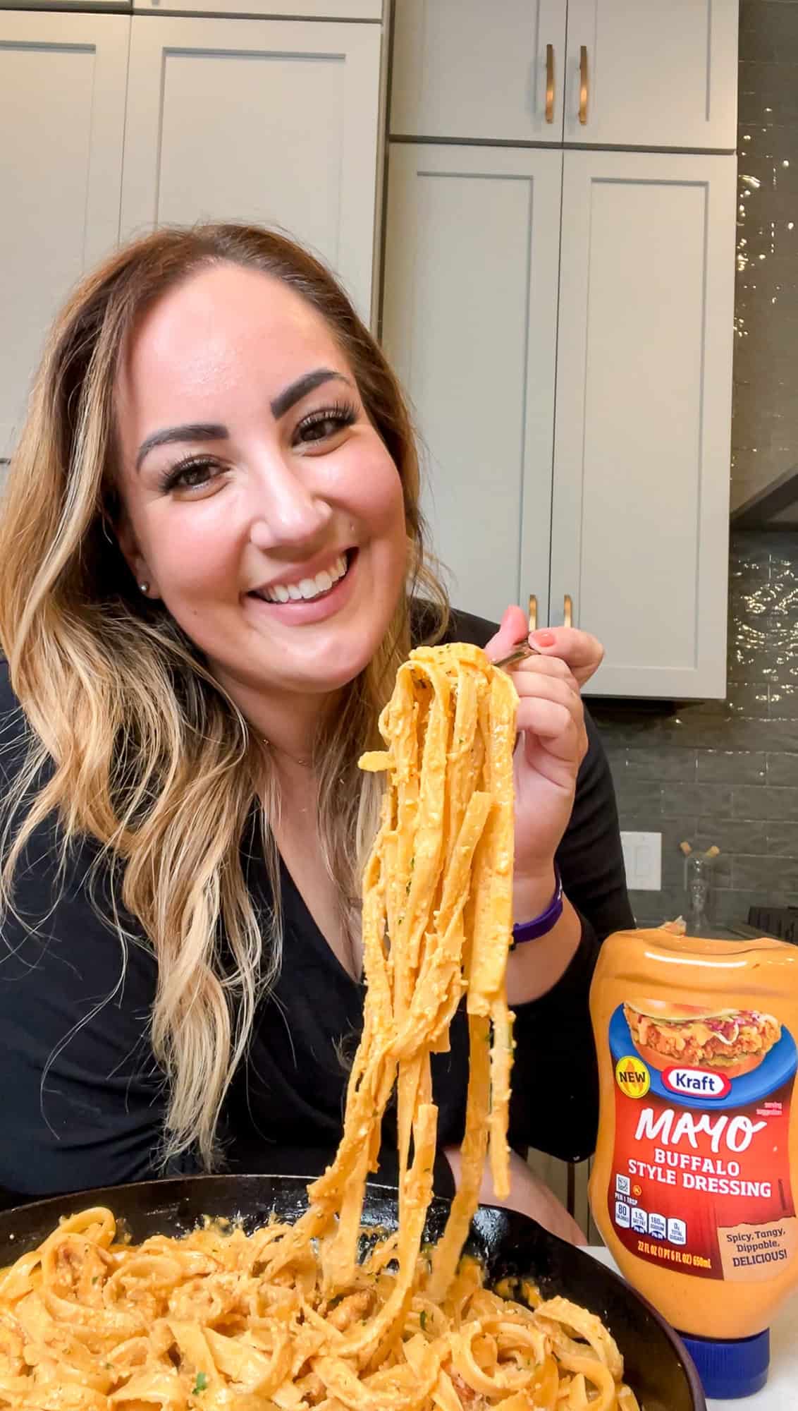 This buffalo chicken pasta recipe combines juicy chicken with tender fettuccine and a creamy, spicy alfredo-style sauce. Ready in 30 minutes! Mallory lifting buffalo chicken pasta from a bowl with a fork.