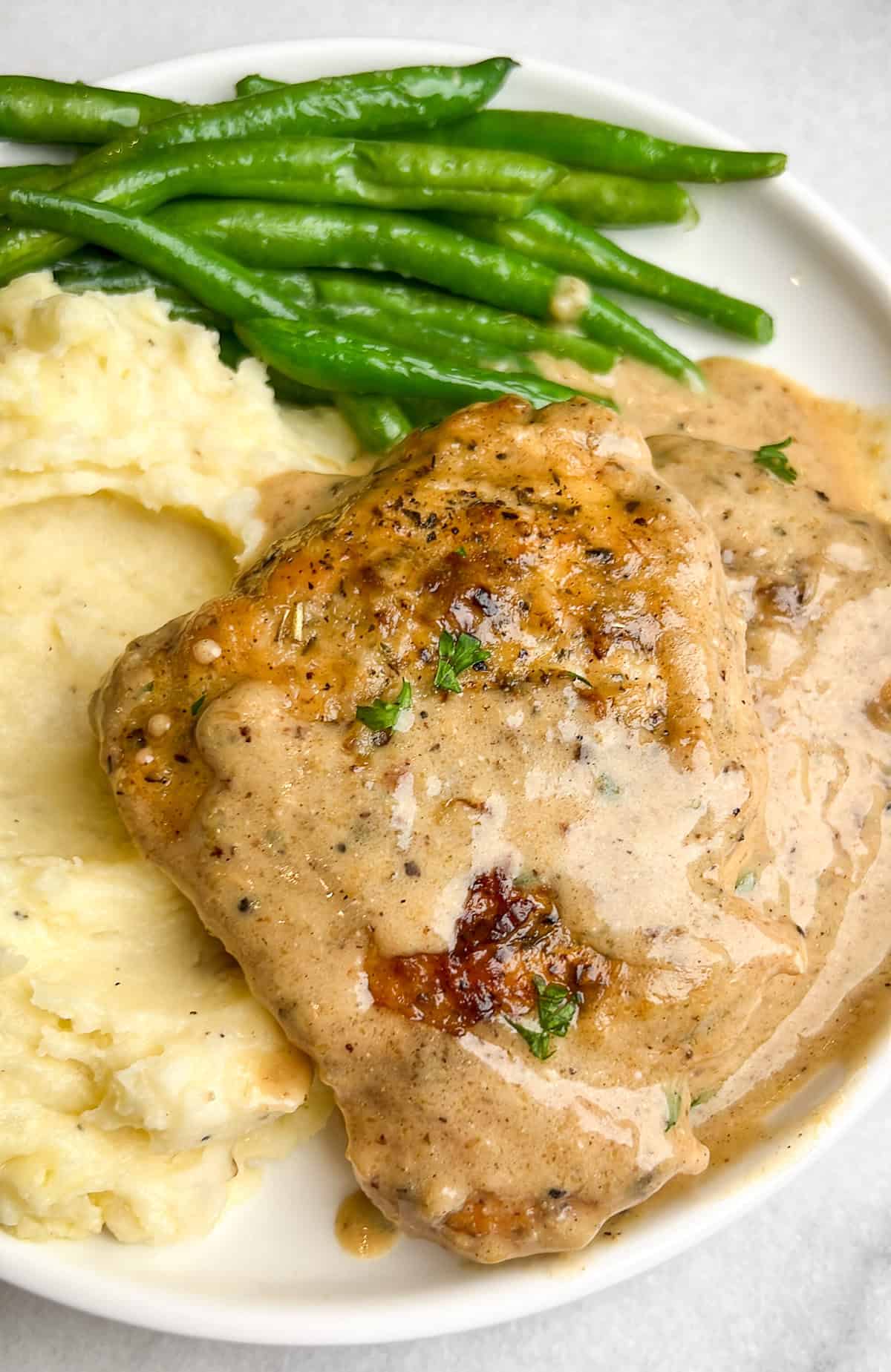 With a rich, mouth-watering sauce made from garlic, heavy cream, and parmesan, this creamy garlic chicken is comfort food at its finest. A plate of creamy garlic chicken with mashed potatoes and green beans
