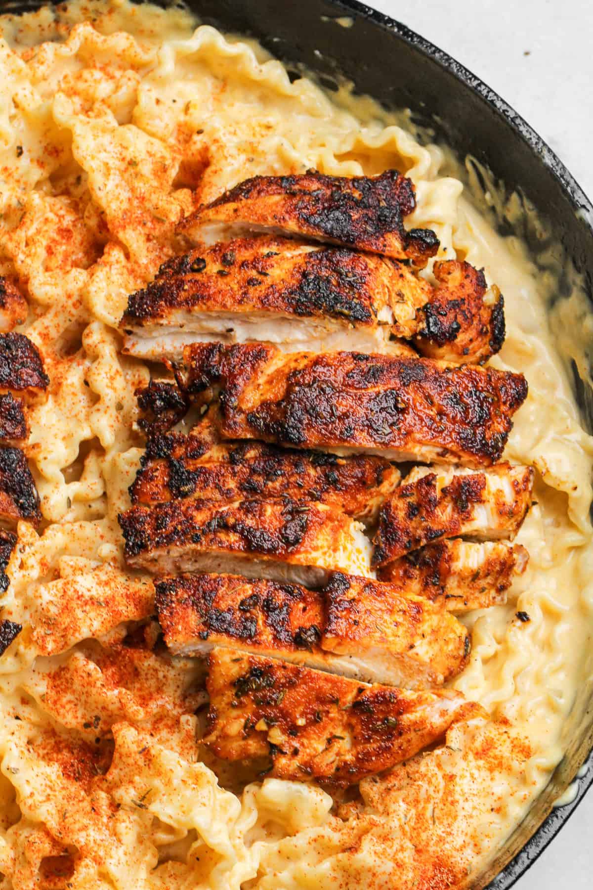 With juicy blackened chicken and a garlicky seasoned alfredo sauce, Blackened Chicken Alfredo is a quick and easy weeknight dinner. Close up of blackened chicken alfredo