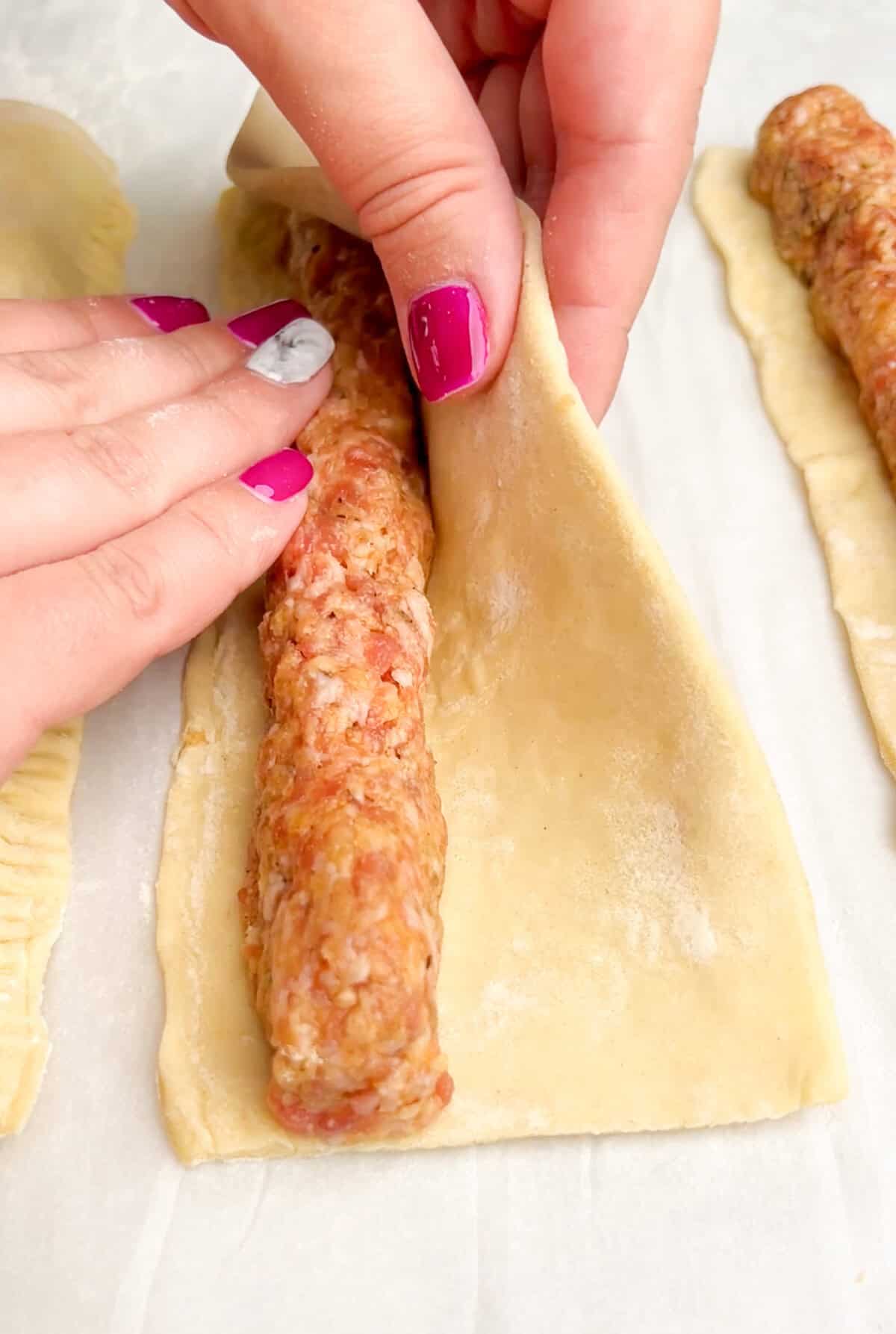 Tucking sausage into the puff pastry and wrapping