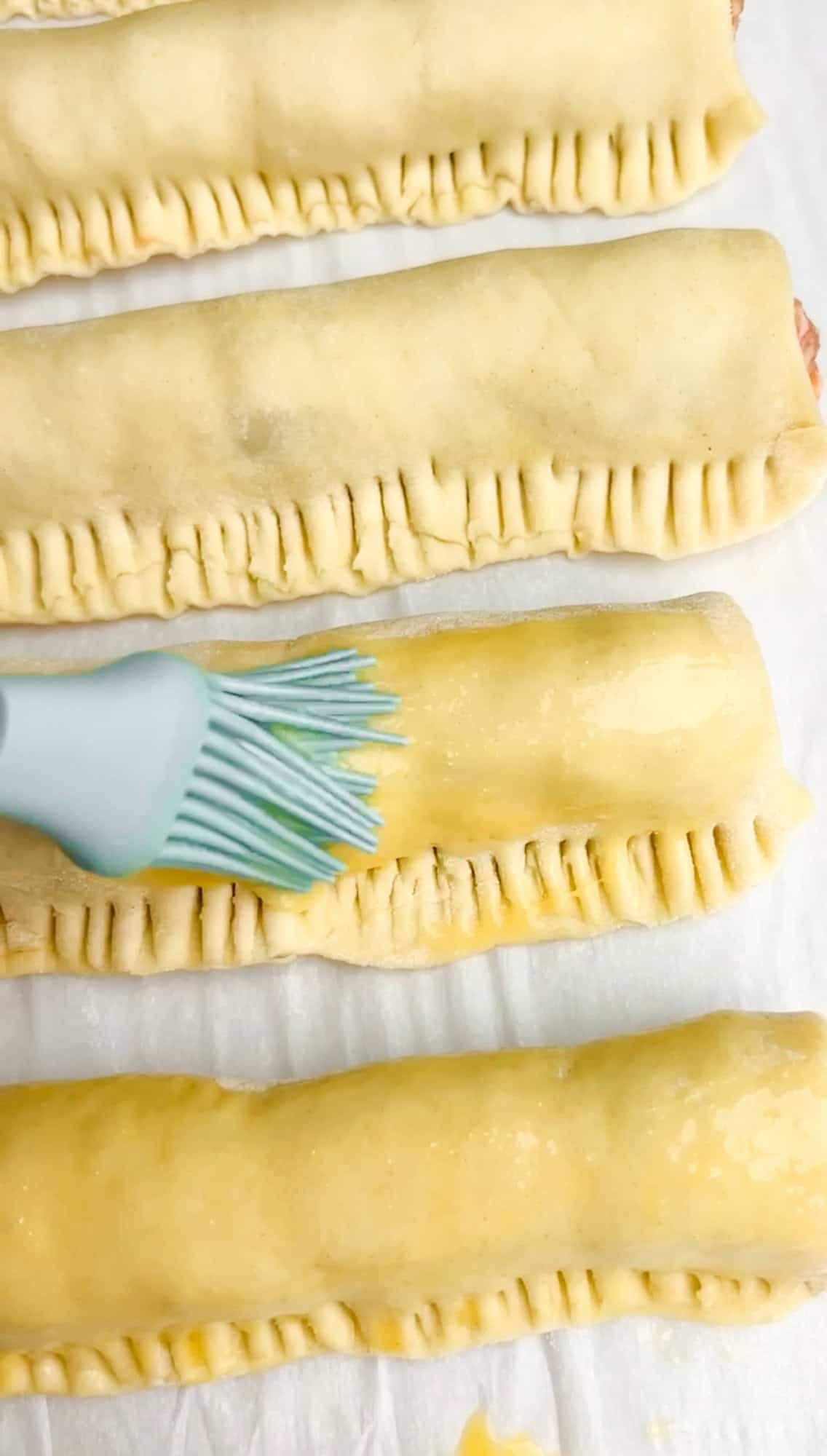 brushing sausage rolls with egg wash