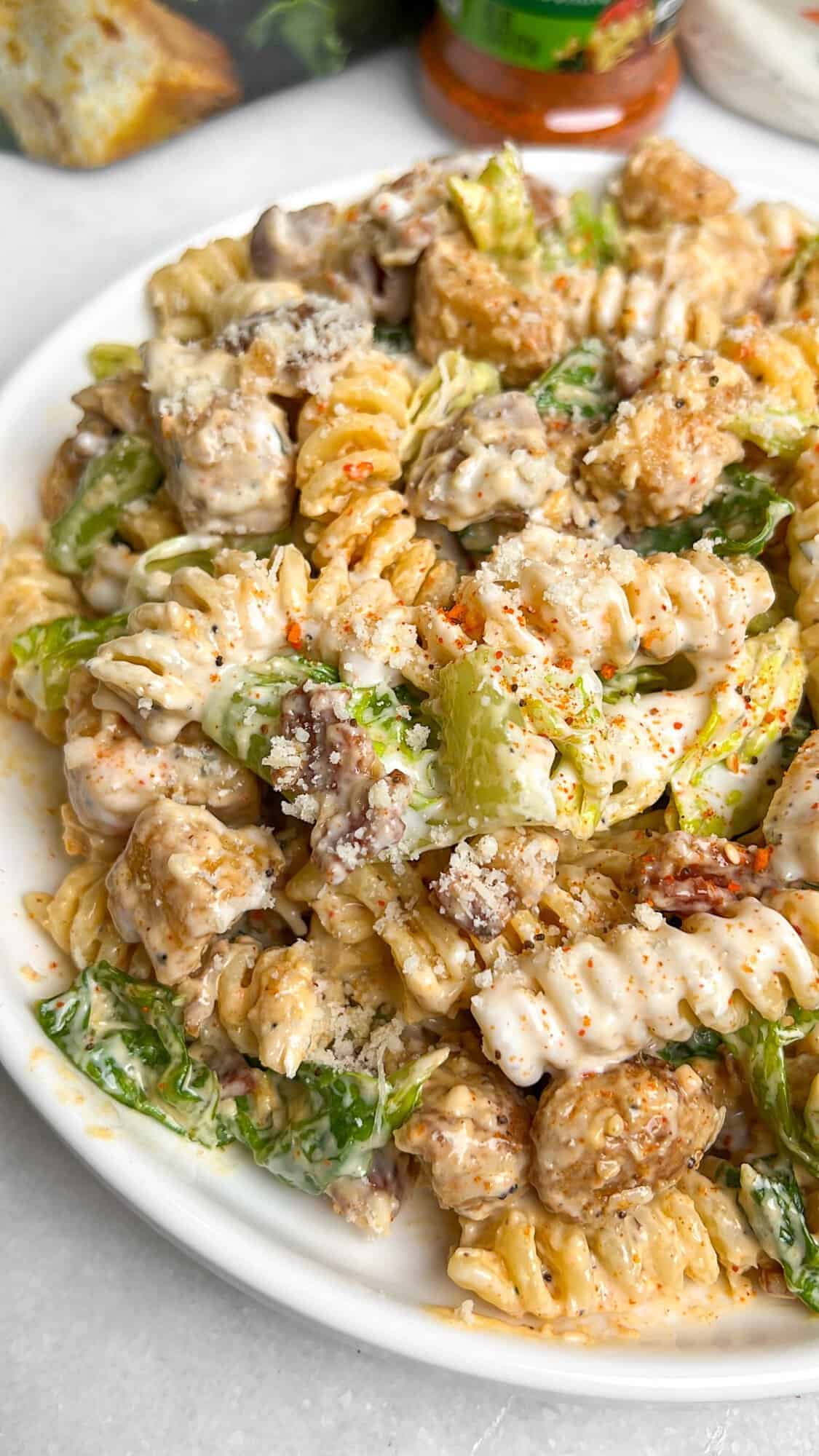 Chicken Caesar Pasta Salad combines tender pasta with parmesan, crispy bacon, juicy chicken, croutons, and crunchy romaine. A plate of chicken caesar pasta salad