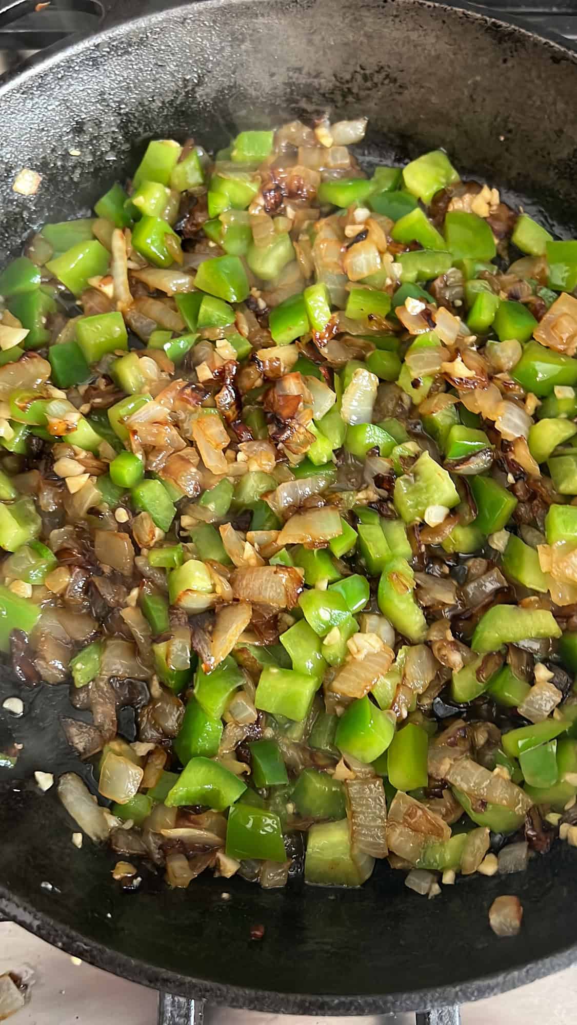 peppers and onions sautéing in a skillet