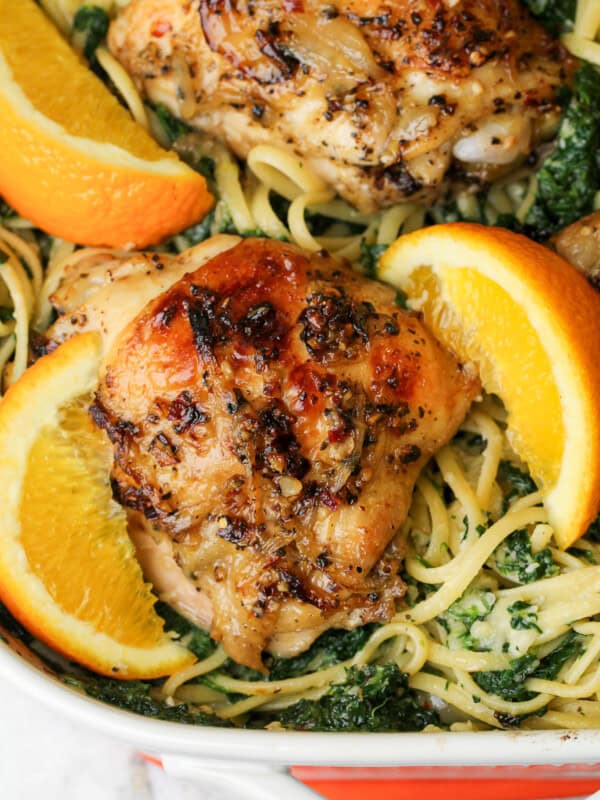 baked chicken with orange wedges over linguini