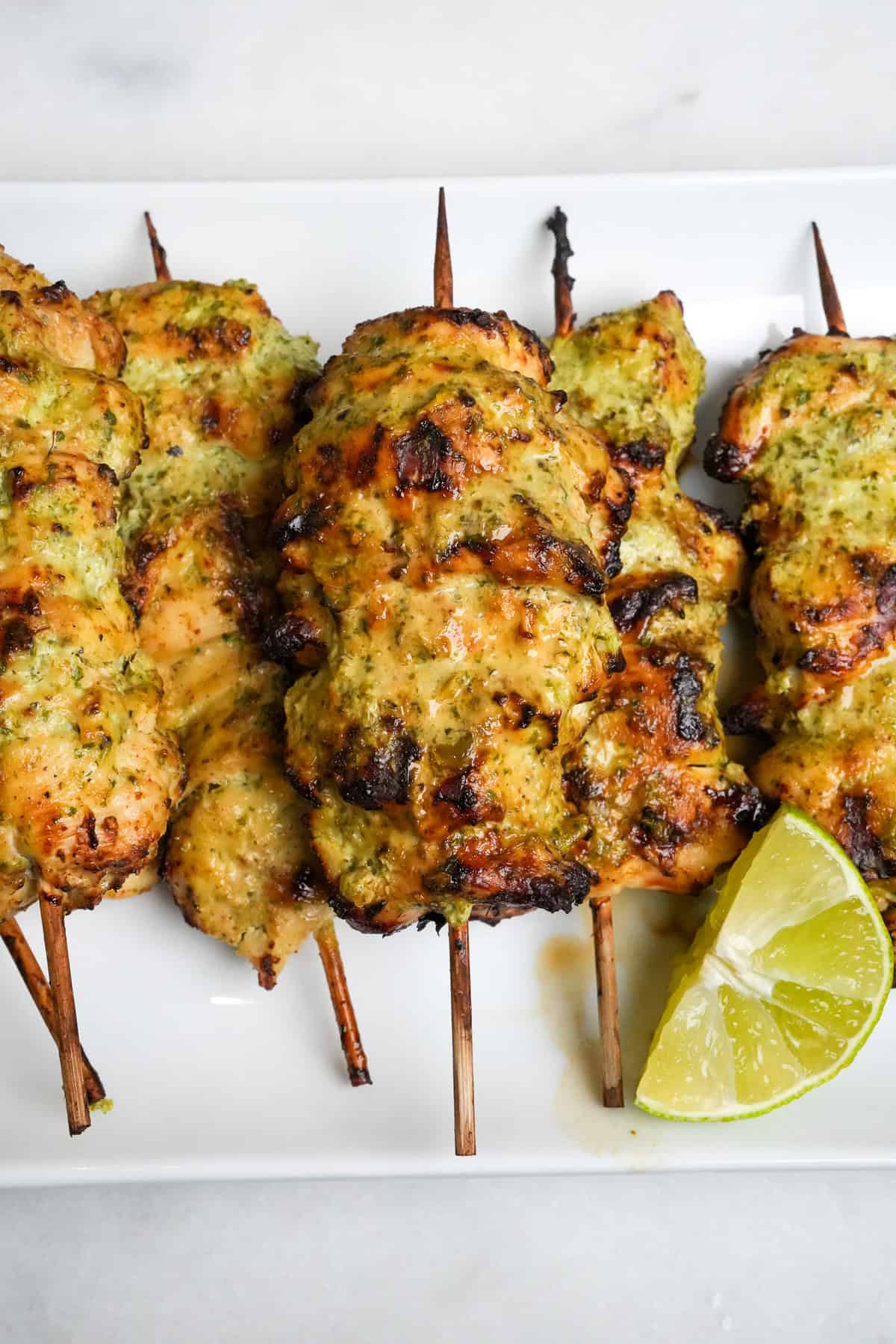 Full of fresh and vibrant flavors, these Cilantro Lime Air Fryer Chicken Skewers are tangy, herby, and so incredibly tender. Air fryer chicken skewers on a white serving platter