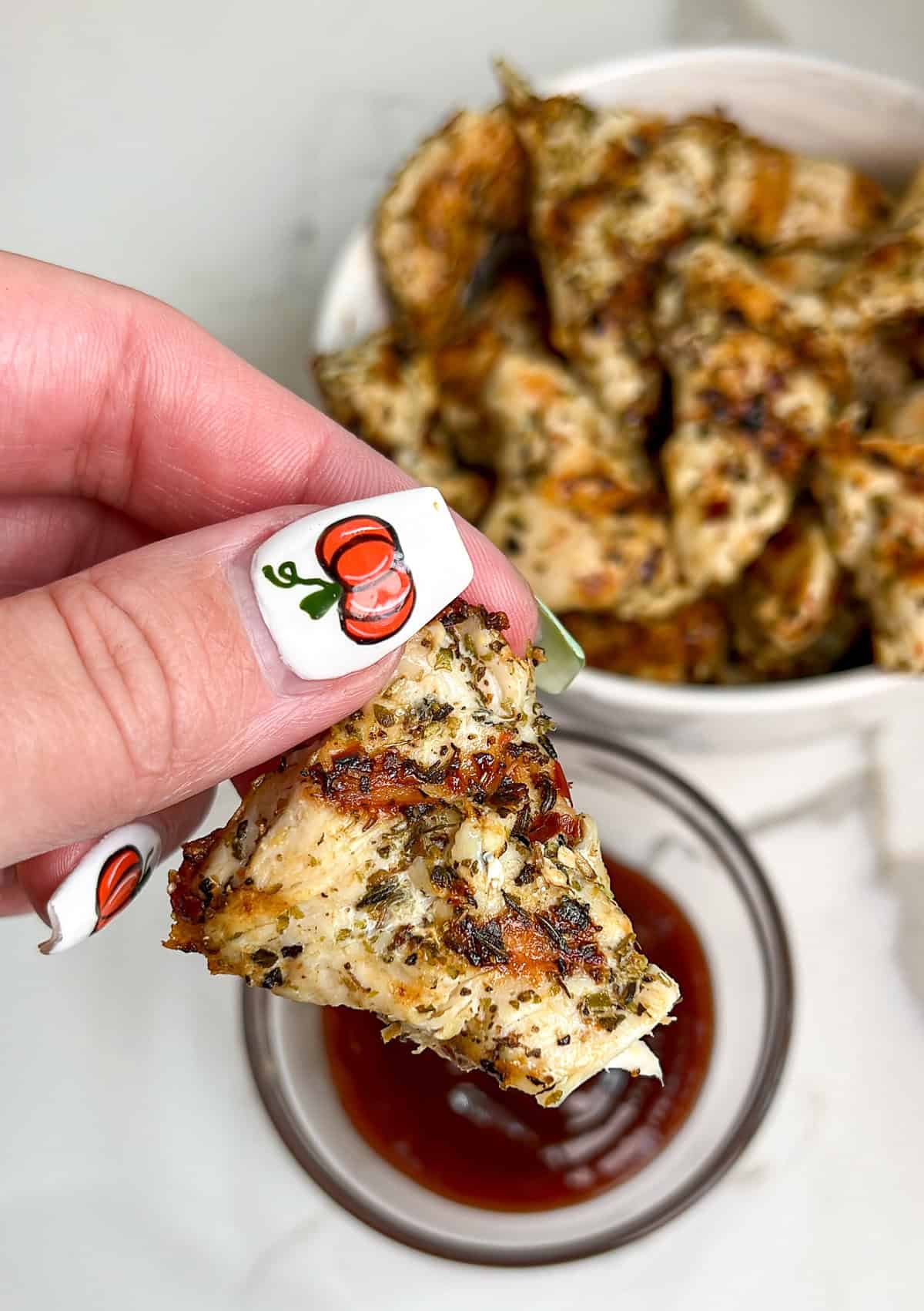 These smoky, tender and juicy chicken nuggets are easily grilled up on the stove in this copycat Chick fil A Grilled Nuggets recipe. A hand holding grilled chicken nuggets