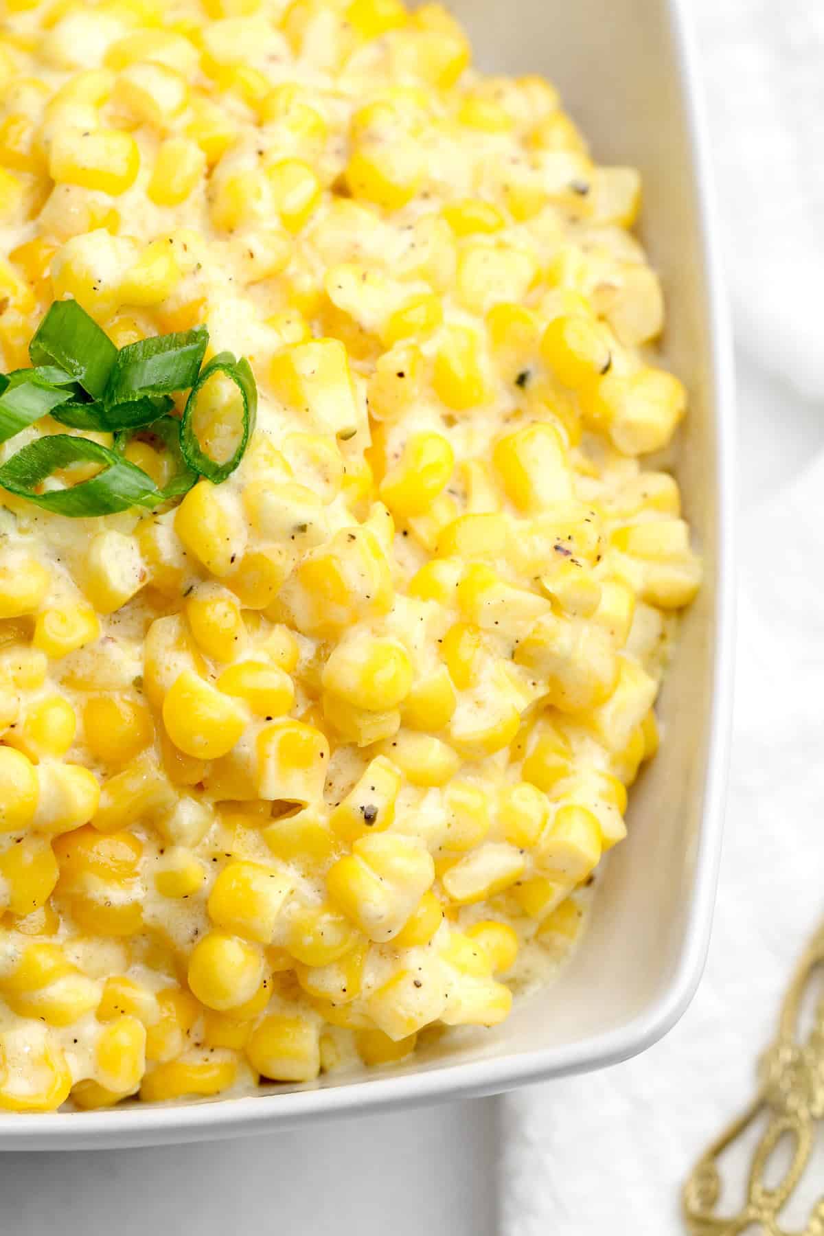 This crock pot creamed corn is sweet and savory with just the right amount of tang. It's the ultimate set-it-and-forget-it holiday recipe. Overhead image of a bowl of creamed corn.