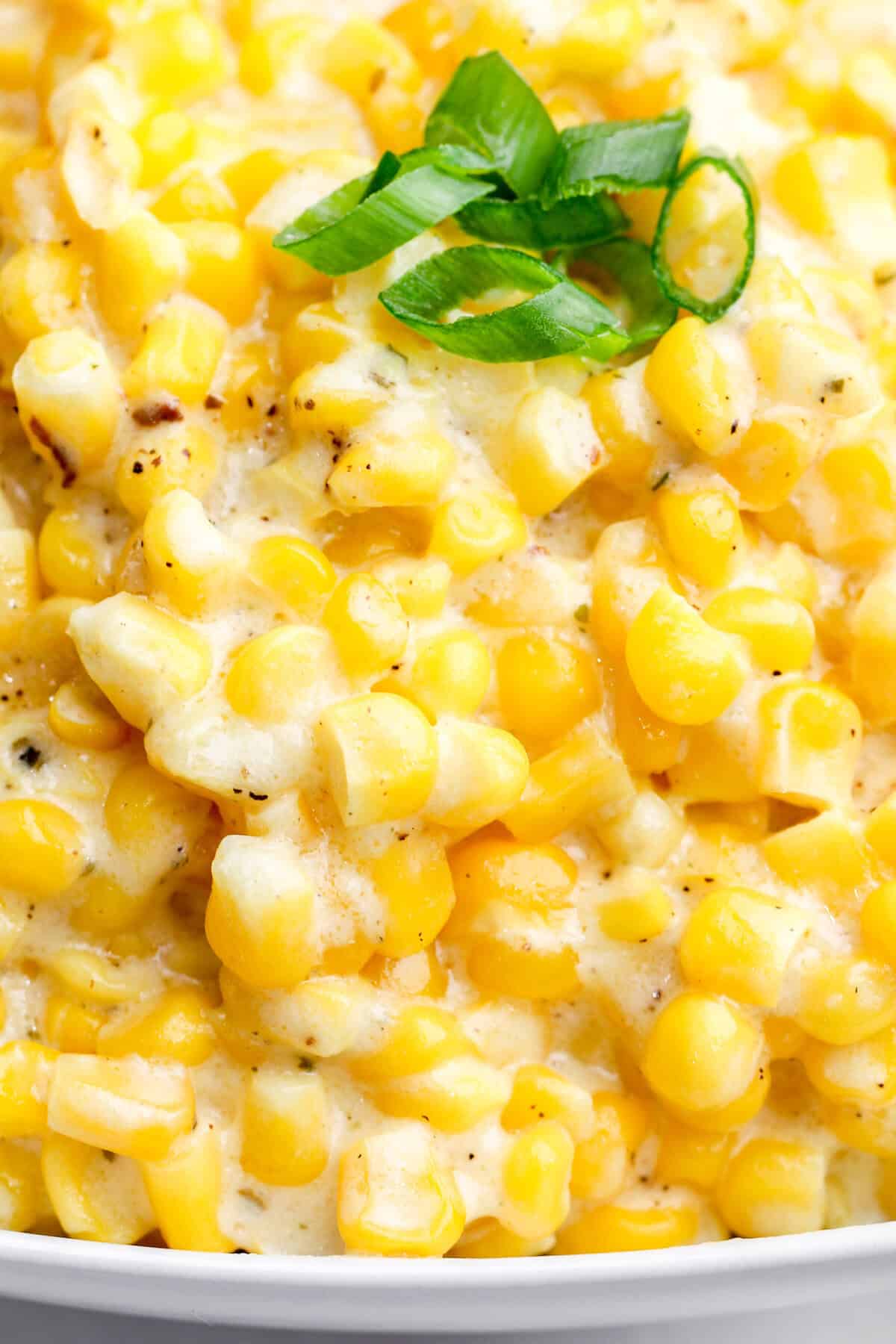 This crock pot creamed corn is sweet and savory with just the right amount of tang. It's the ultimate set-it-and-forget-it holiday recipe. Close-up image of a bowl of crock pot creamed corn.