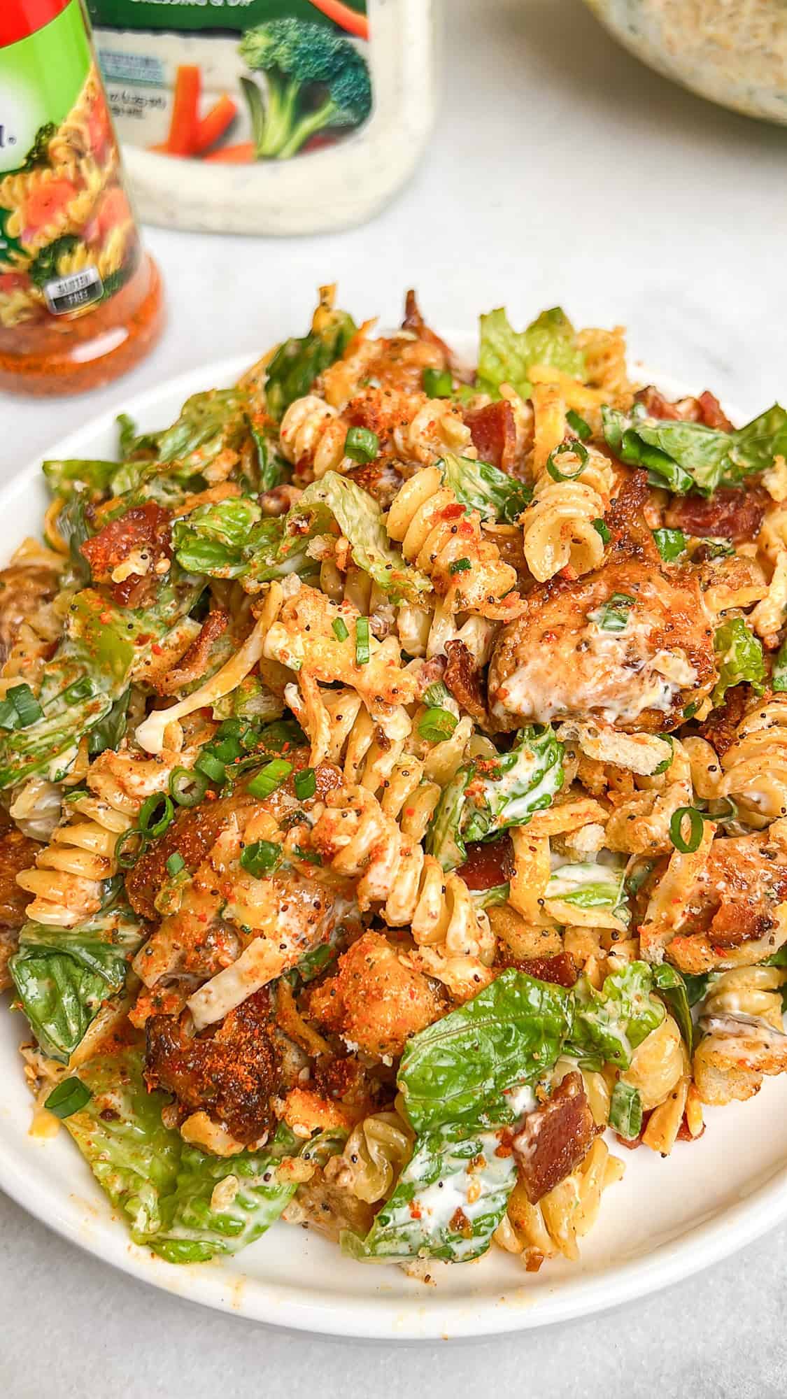 Diced chicken, crispy bacon, crunchy romaine lettuce, and croutons are tossed with ranch dressing in this Chicken Bacon Ranch Pasta Salad. Close up of a plate of chicken bacon ranch pasta salad
