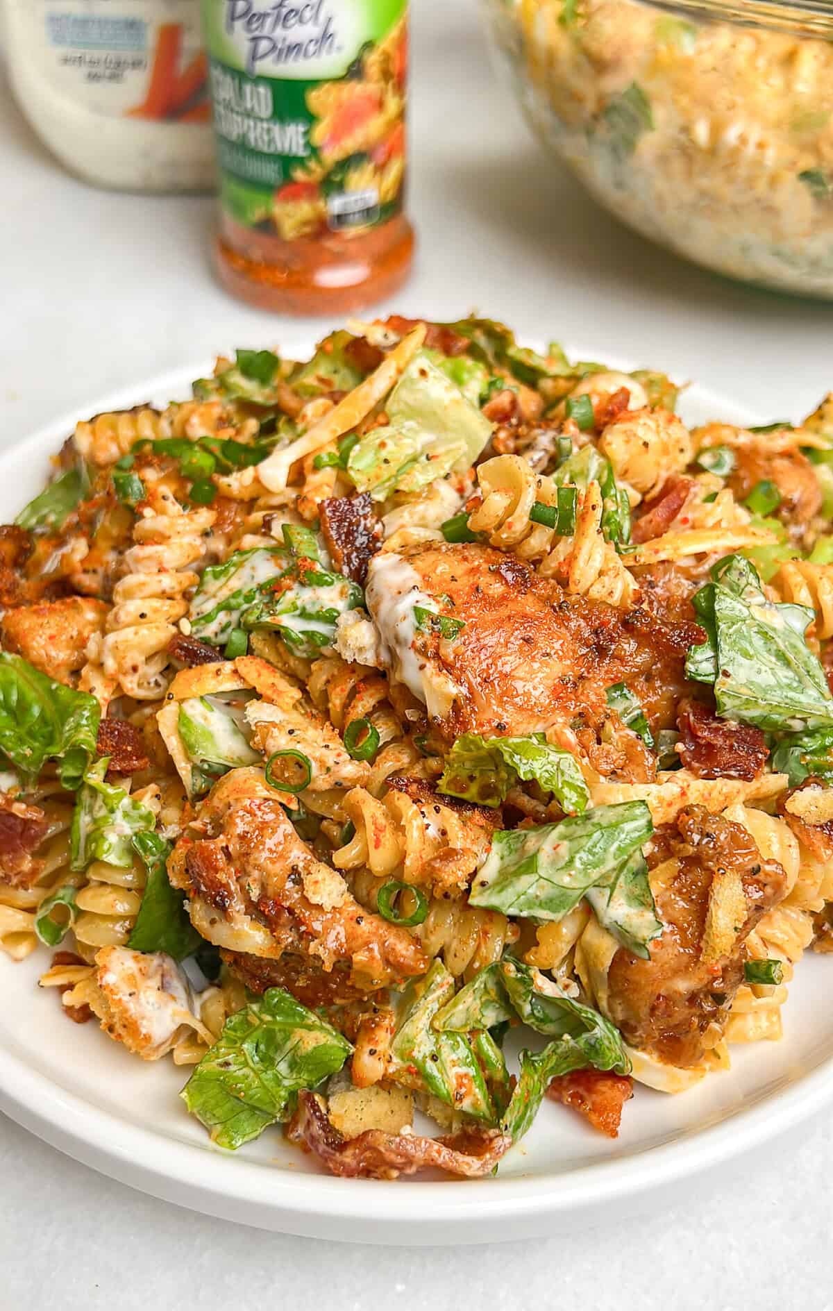 Diced chicken, crispy bacon, crunchy romaine lettuce, and croutons are tossed with ranch dressing in this Chicken Bacon Ranch Pasta Salad. A plate of chicken bacon ranch pasta salad
