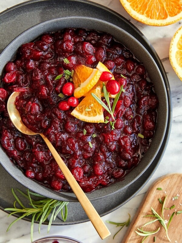 A serving bowl full of homemade cranberry sauce with a golden spoon.