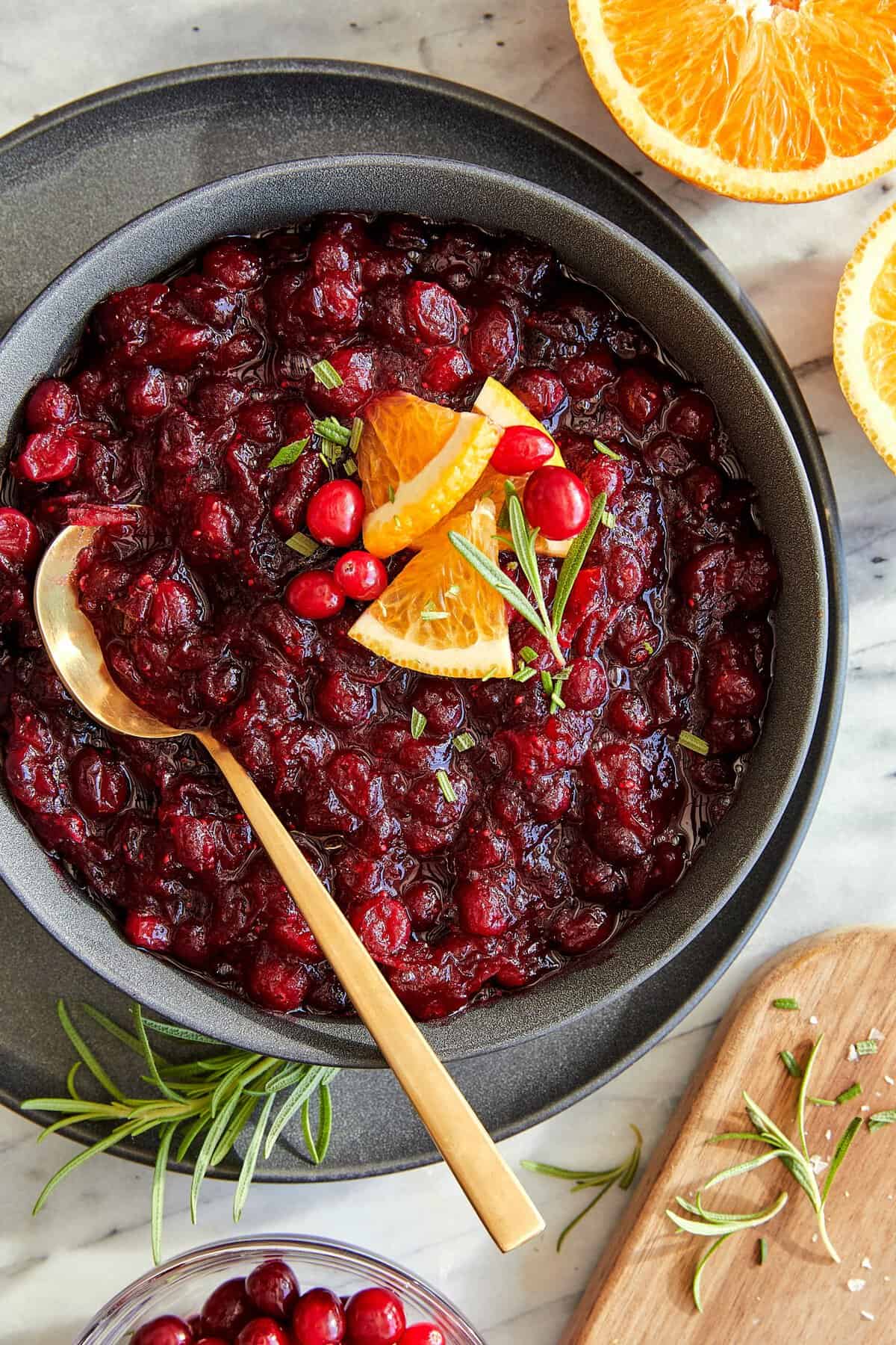 Skip the canned stuff this year. This 20-minute cranberry sauce is made from fresh cranberries, with a hint of orange and warming cinnamon. A serving bowl full of homemade cranberry sauce with a golden spoon.