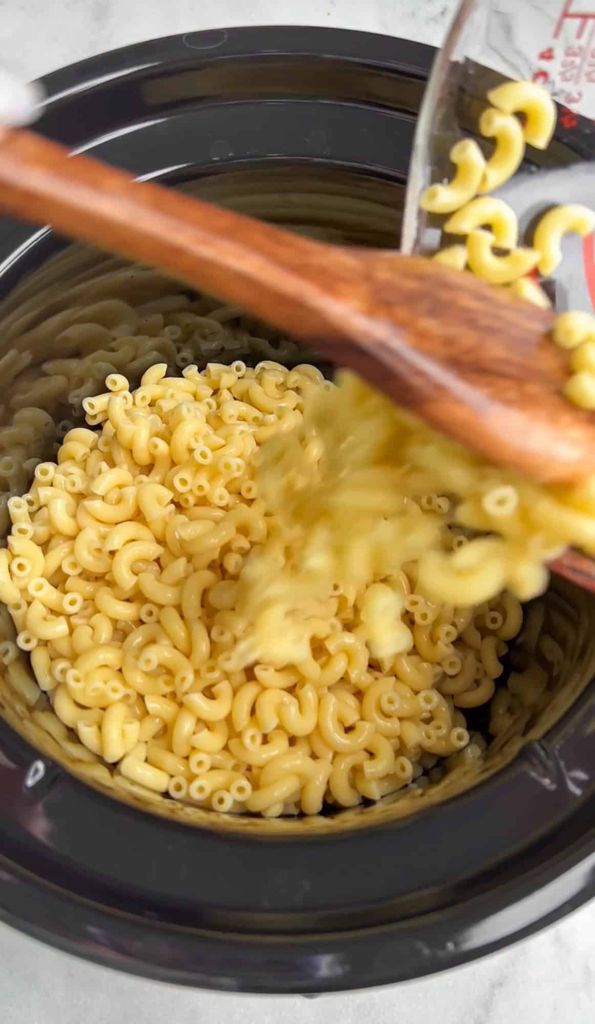 macaroni being poured into a slow cooker