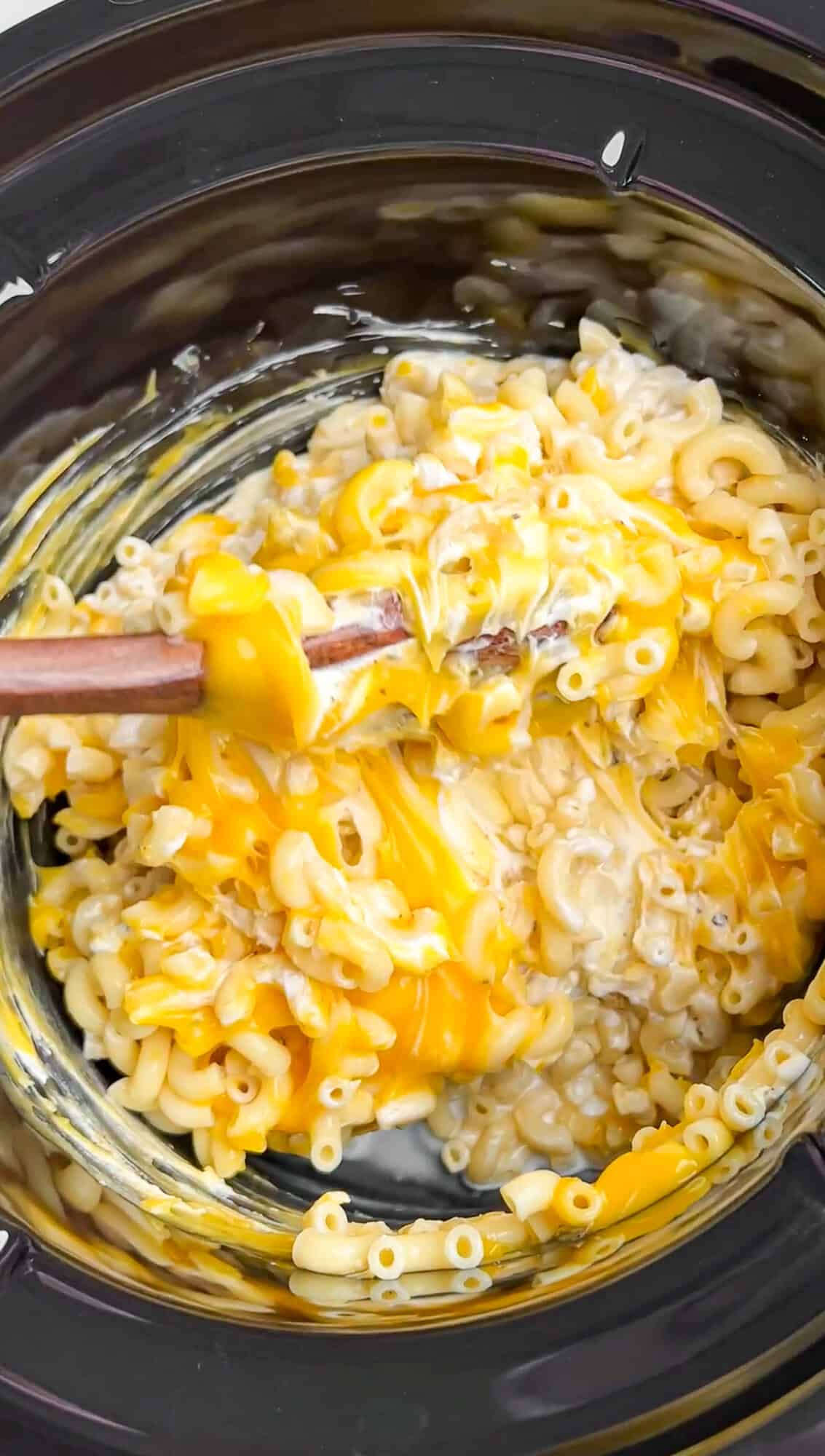 stirring the mac and cheese ingredients in the slow cooker