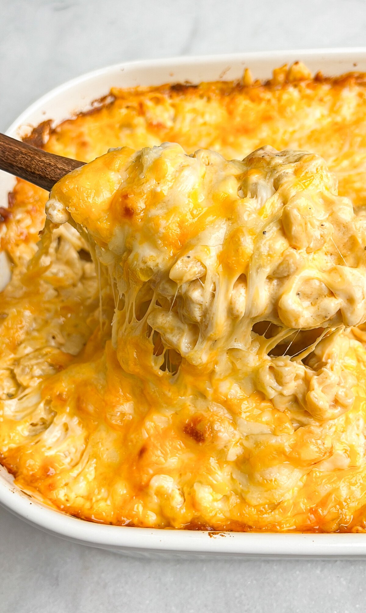 gooey macaroni and cheese being lifted out of pan with a spoon