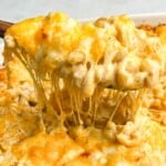 macaroni and cheese being lifted out of a pan with a spoon