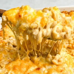 macaroni and cheese being lifted out of a pan with a spoon