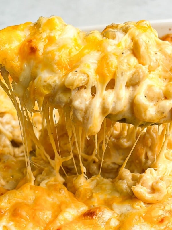 macaroni and cheese being lifted out of a pan with a spoon