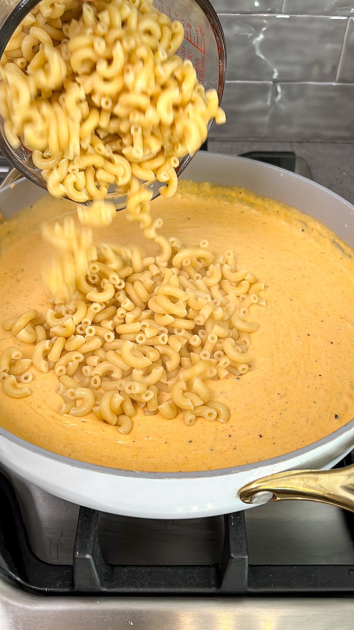 adding the cooked macaroni into the cheese sauce