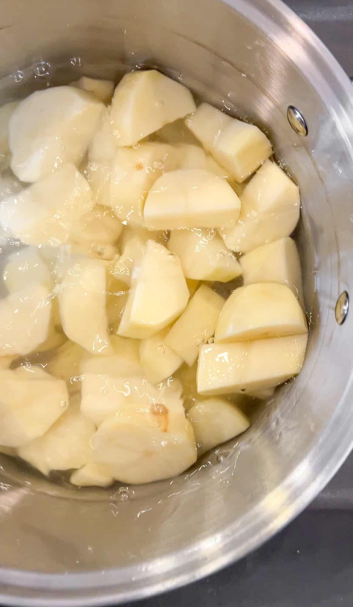 filling up a large pot of water with diced potatoes