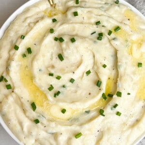 a bowl of whipped mashed potatoes with pats of butter