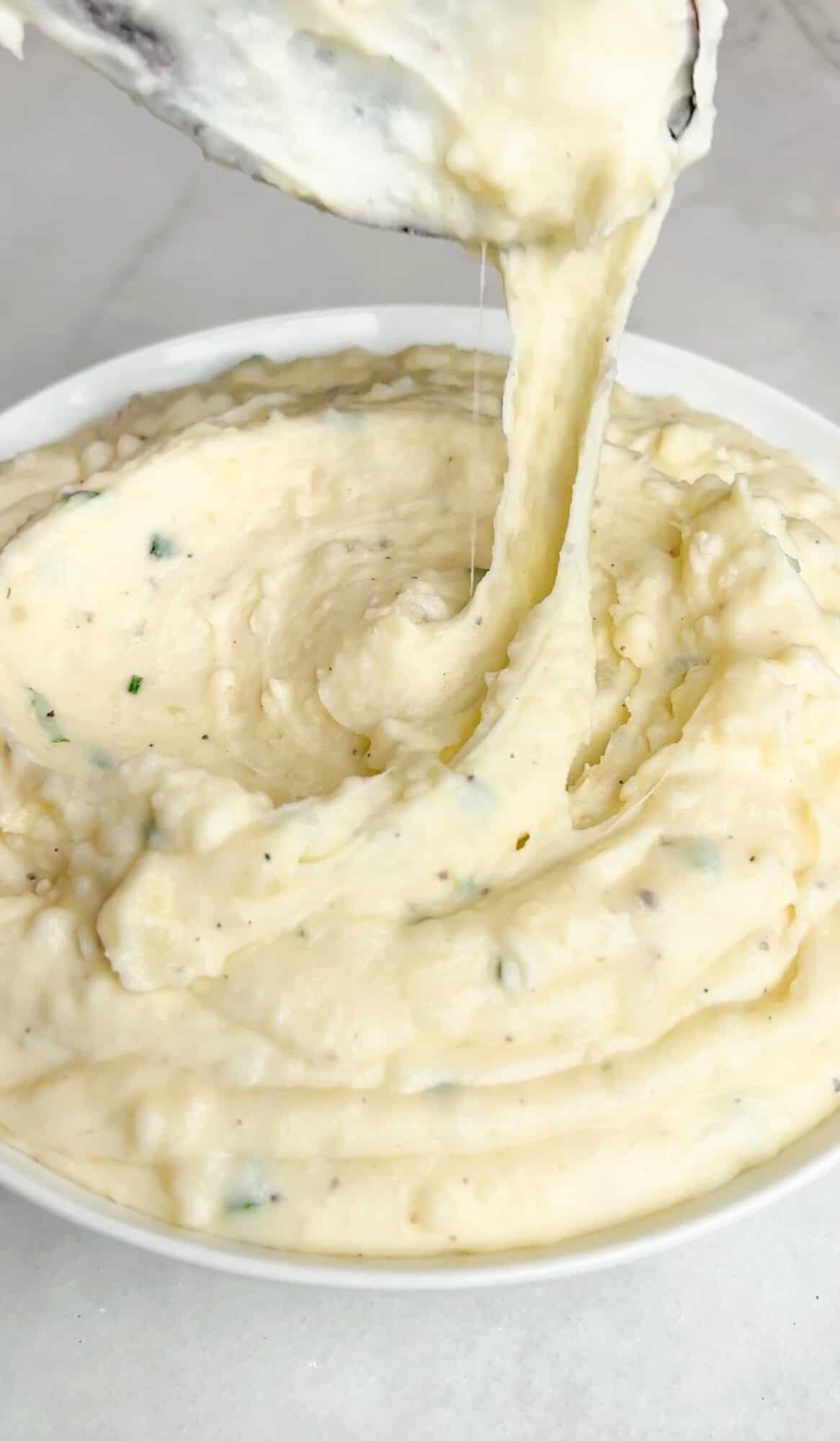 gooey whipped mashed potatoes hanging off a spoon over a bowl