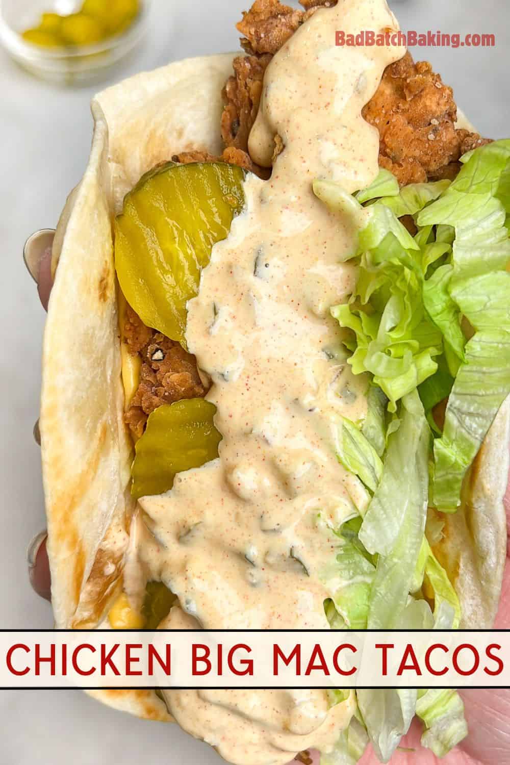 a fried chicken taco with sauce, lettuce and pickles