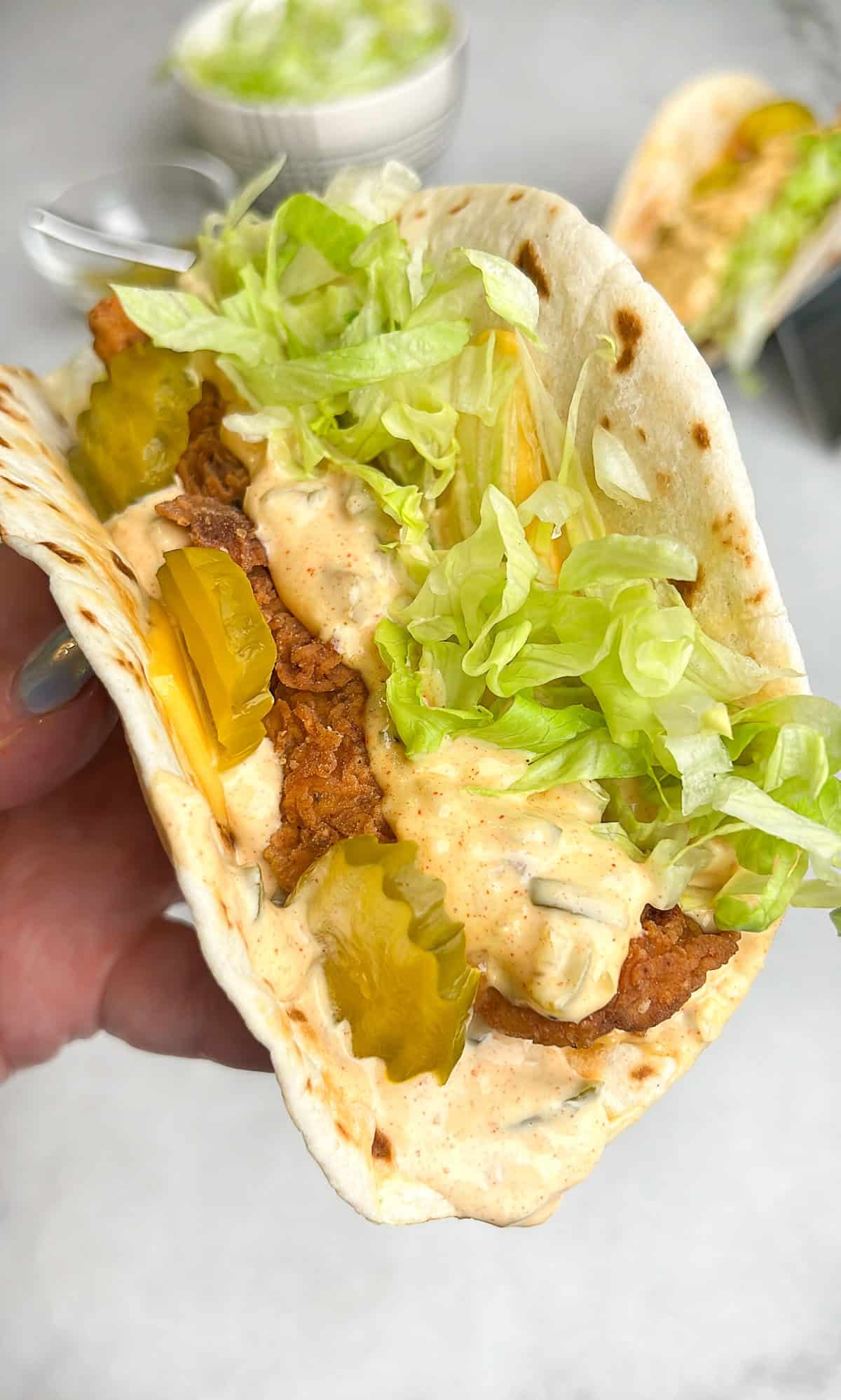 chicken big mac taco being held in a hand