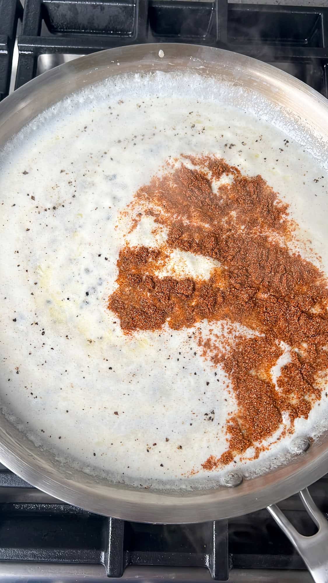 making alfredo sauce in a pan with seasoning