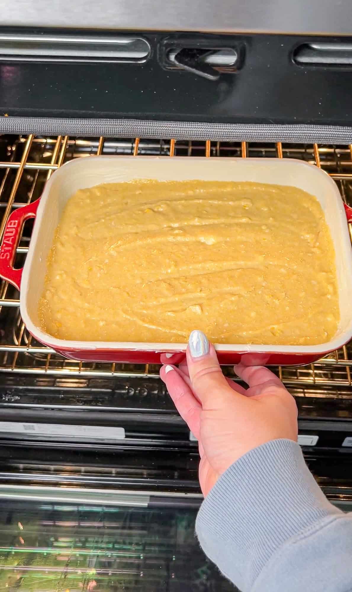 putting the pan of cornbread in the oven