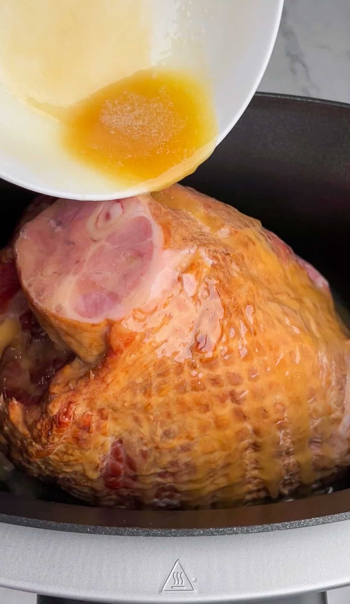 butter and honey being poured over the ham in a slow cooker