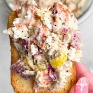 chicken salad piled on a cracker being held by hand.