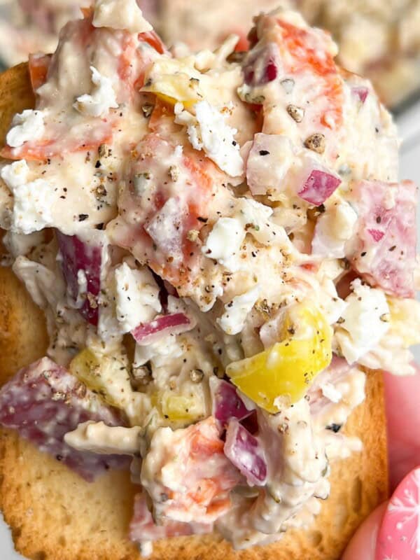 chicken salad piled on a cracker being held by hand.